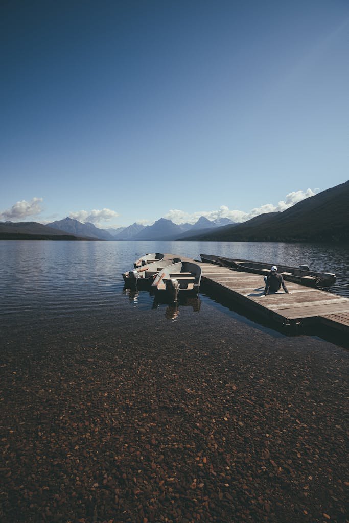 Peaceful Lake McDonald view with mountains, boats, and a clear sky in Glacier National Park, Montana.